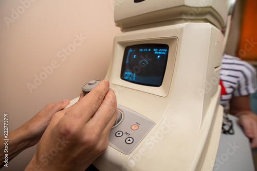 The doctor's hands control the apparatus for testing the vision behind which the patient is sitting