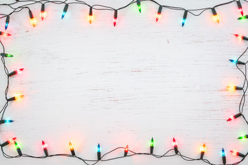 Christmas lights bulb frame decoration on white wood. Merry Christmas and New Year holiday background. top view