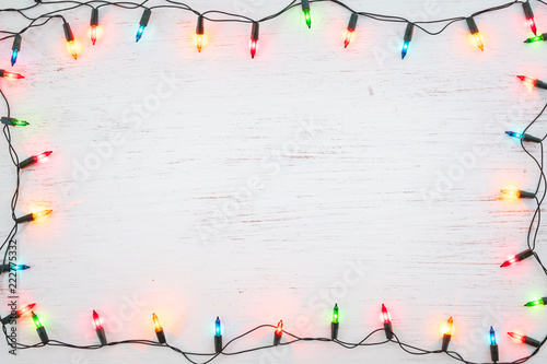 Christmas lights bulb frame decoration on white wood. Merry Christmas and New Year holiday background. top view photo