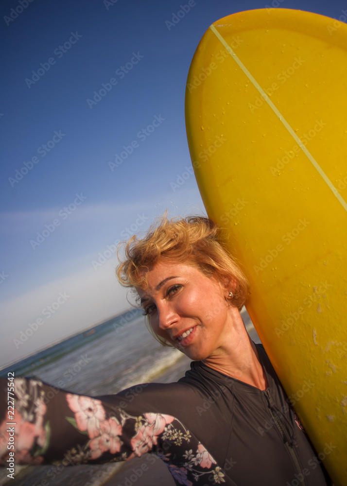 young attractive and happy blonde surfer woman in swimsuit holding surf board in the beach taking self portrait selfie picture smiling cheerful enjoying holidays