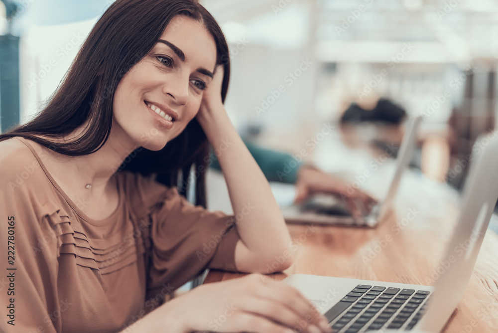 Portrait of outgoing girl typing on laptop at desk while touching head with arm. Cheerful lady during work concept Portrait of outgoing girl typing on laptop at desk while touching head with arm. Cheerful lady during work concept