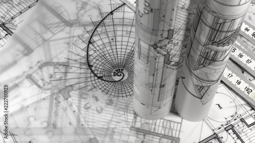 Blueprints - rolls of architectural drawings, yardstick - folding ruler and drawing of the golden section smoothly rotate on the surface of the architectural drawings