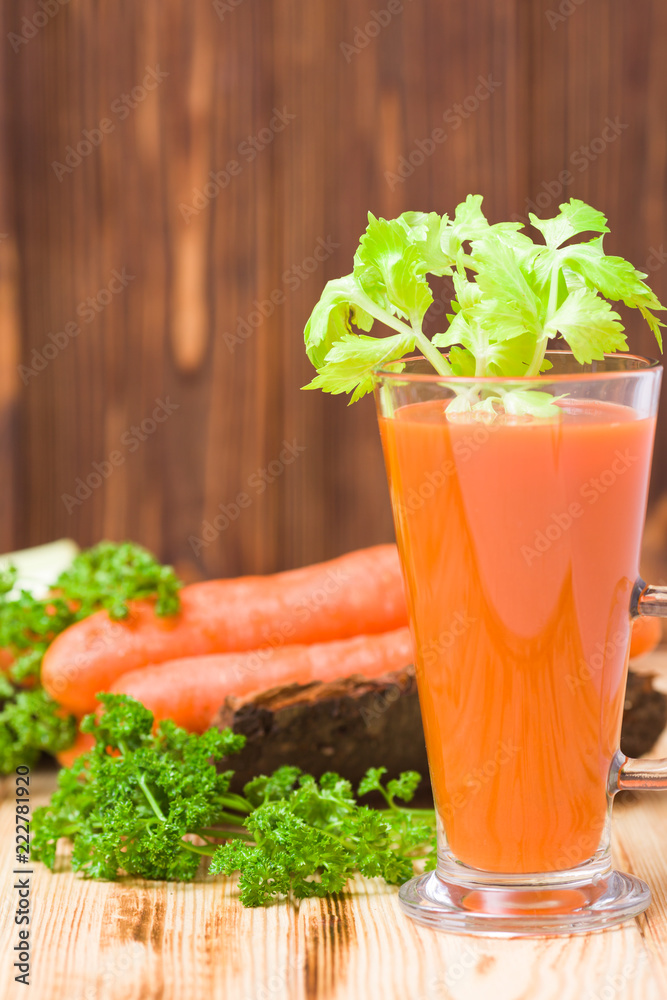 Carrot and celery juice with fresh vegetables on bark plates on wooden background. Carrot and celery juice with fresh vegetables on bark plates on wooden background.