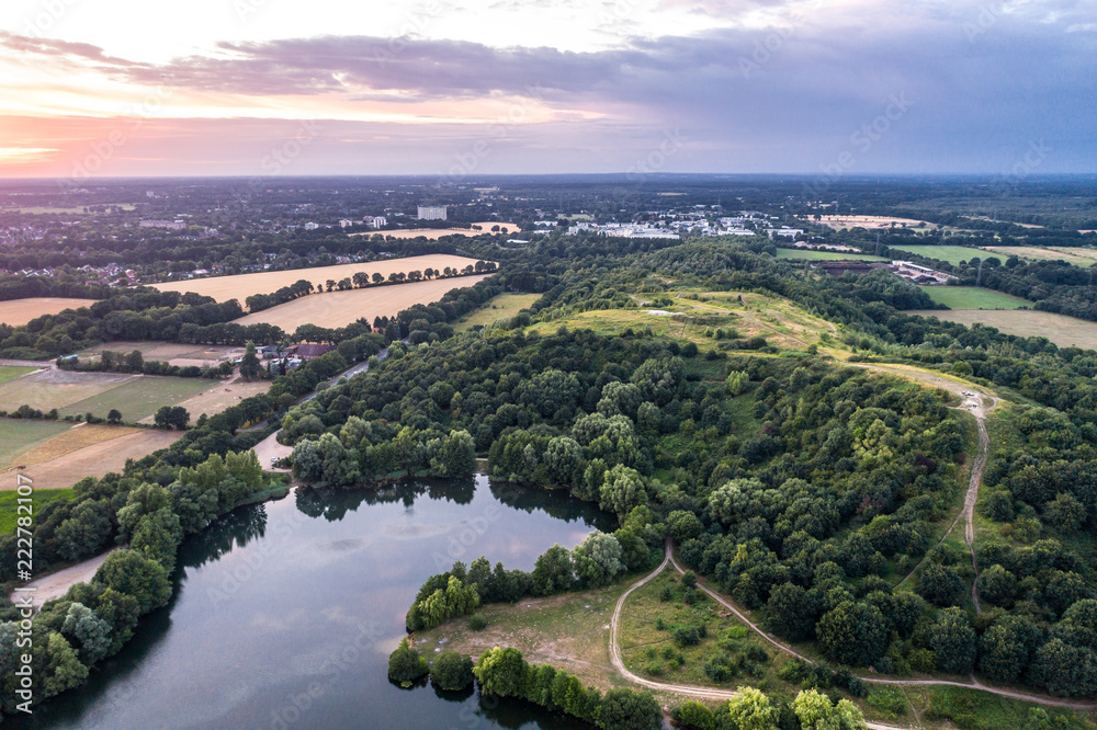 Aerial view of amazing sunset over the park in Germany. Hill and lake from birds eye view.  