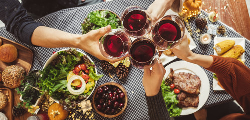 Group of young people celebrating Christmas thanksgiving party dinner with clinking glass of wine, top view