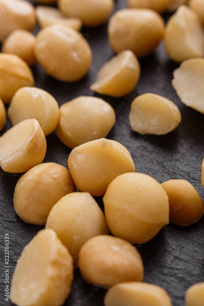 delicious macadamia nuts on a dark stone background delicious macadamia nuts on a dark stone background