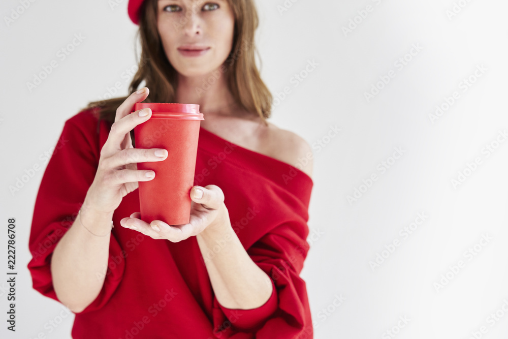 Beautiful woman with long hair wearing red hat and sweater holds paper disposable coffee cup. Space for design template layout mock-up. Beautiful woman with long hair wearing red hat and sweater holds paper disposable coffee cup. Space for design template layout mock-up.