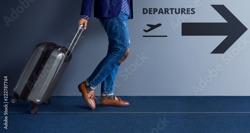 Traveling Concept, Young Traveler Walking with Suitcase and Follow the Departures Sign in the Airport photo
