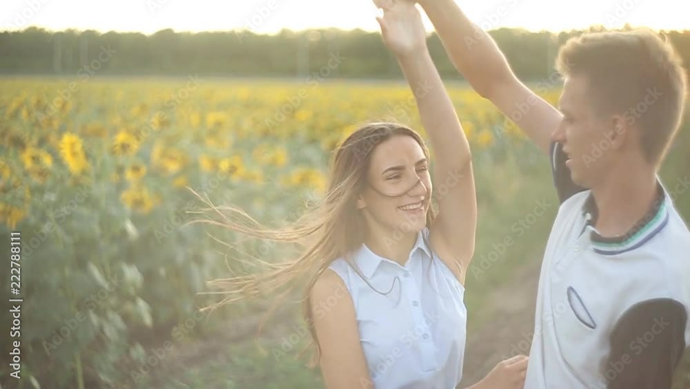 young couple in love dancing in the evening at sunset in a field of sunflowers. young couple in love dancing in the evening at sunset in a field of sunflowers.