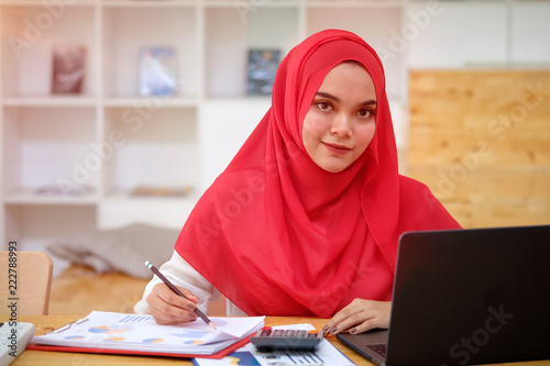 Attractive young Asian wearing red hijab working her laptop.