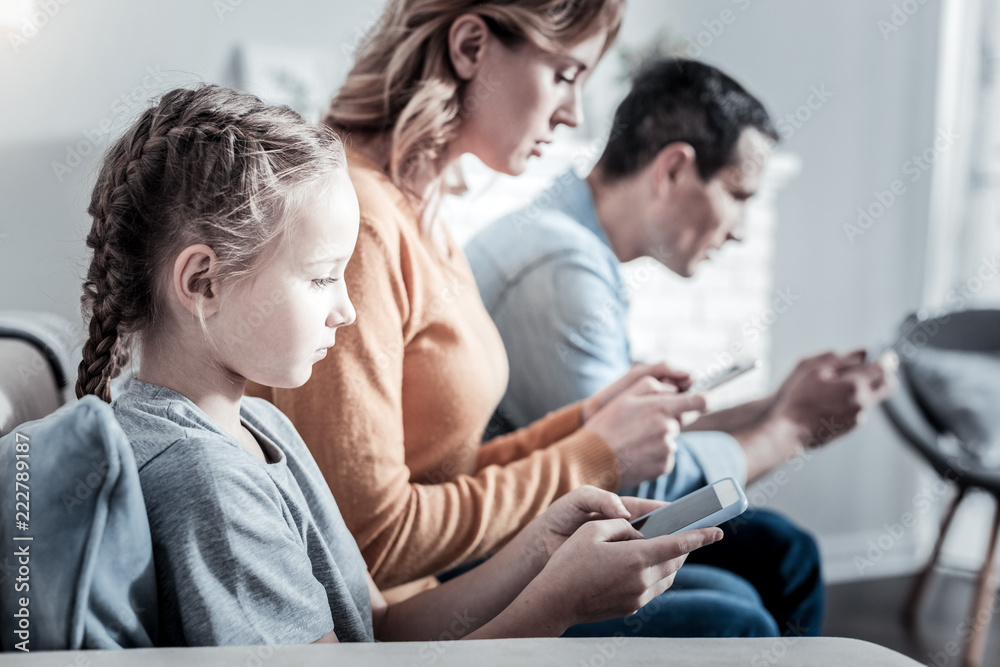 No communication. Ordinary modern family searching on Internet while sitting on the sofa No communication. Ordinary modern family searching on Internet while sitting on the sofa