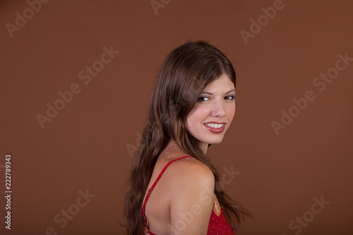Naturally thin healthy brunette girl in the studio with a brown background