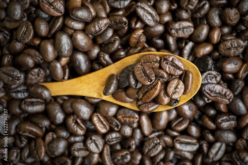 Heap of roasted coffee beans with wooden spoon