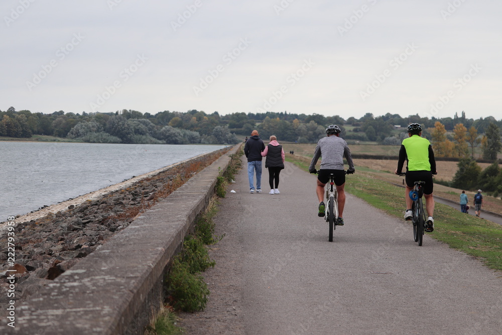 Fototapeta premium family walks, cycling and jogging along a pathway .children palying on bikes and scooters