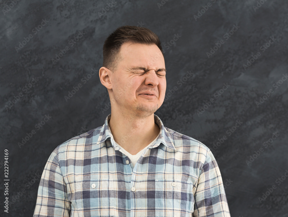 Young man expressing disgust at studio background