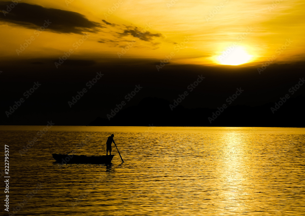 Silhouette of unidentifiable boatman checking fishing nets in Lopud bay with sun setting over Sipan island, Croatia