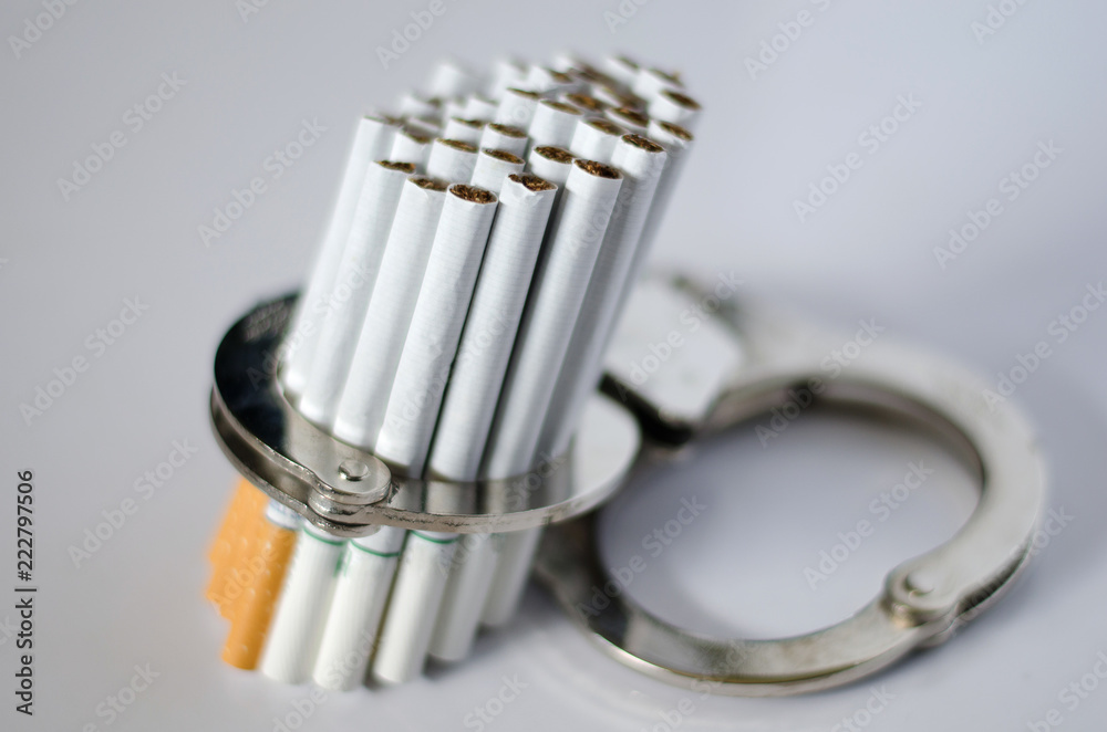 Bunch of cigarettes in the handcuffs on the white floor. No Tobacco day concept Bunch of cigarettes in the handcuffs on the white floor. No Tobacco day concept