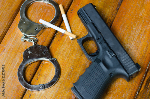 Guns, handcuffs, cigarette Placed on a wooden table