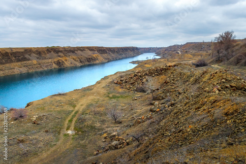 The old abandoned sandstone quarry with long blue lake and unpaved road at the bottom
