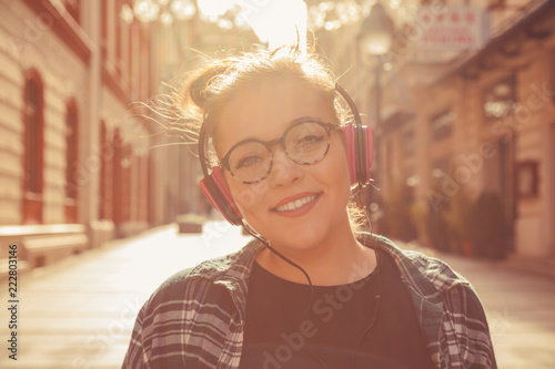 Beautiful woman listening music in headphones outdoors.