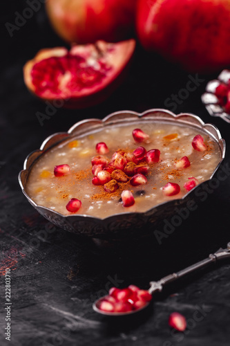 Turkish Dessert Ashura With Pomegranate, Noah's Pudding on Dark Wooden Background