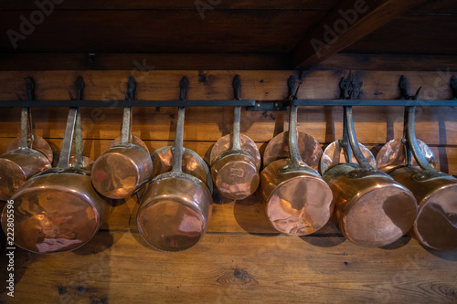 Old copper pans on a wooden wall in a european castle kitchen
