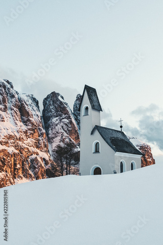 Sonnenuntergang im Winter an der verschneiten Kapelle am Grödner Joch in Südtirol