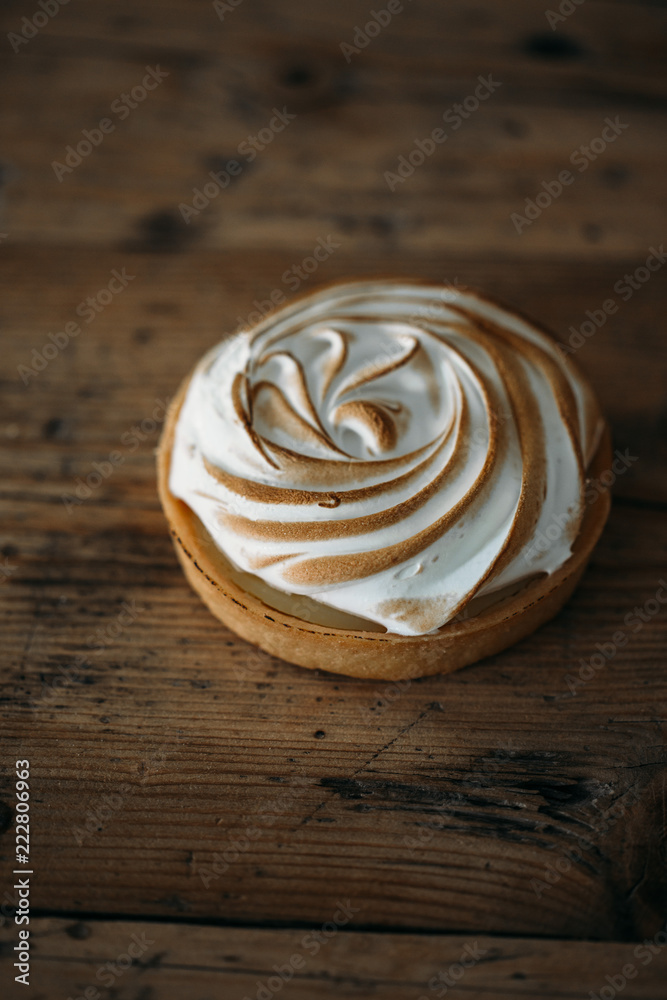 Tartlet with lemon cream and meringue on old rustic wooden background Tartlet with lemon cream and meringue on old rustic wooden background