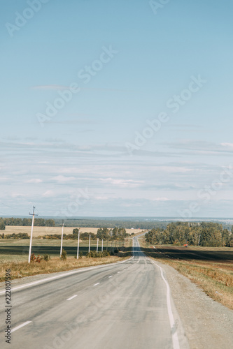 The road among the fields and mowed grass. Russian plains, autumn landscape in the afternoon