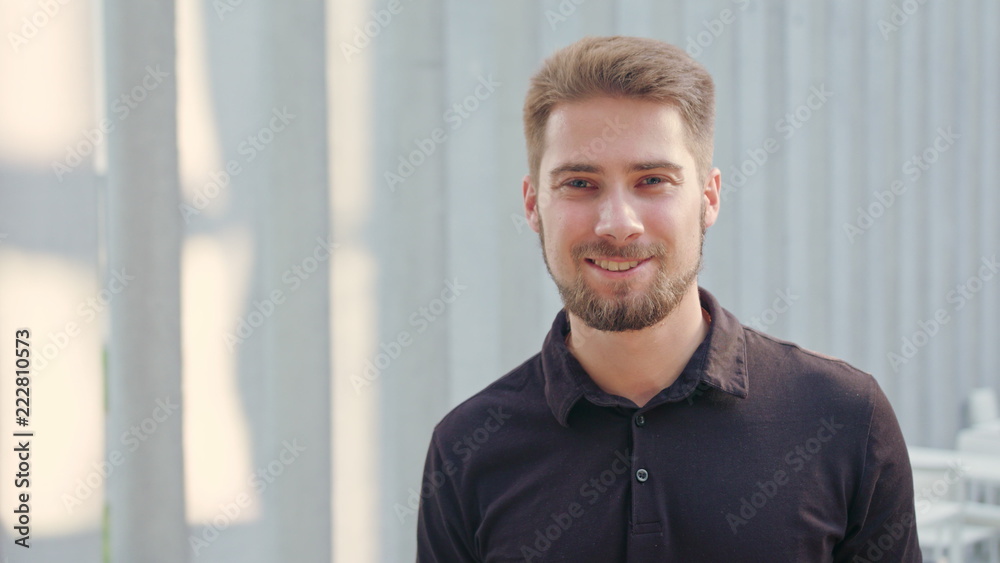 Obraz premium A happy smiling man with a beard standing against a white blurry background. Medium shot. Soft focus