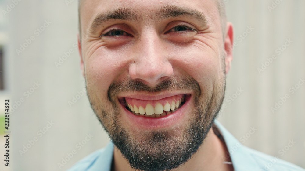 Fototapeta premium A man with a beard smiling against a blurry white background. Close-up shot. Soft focus