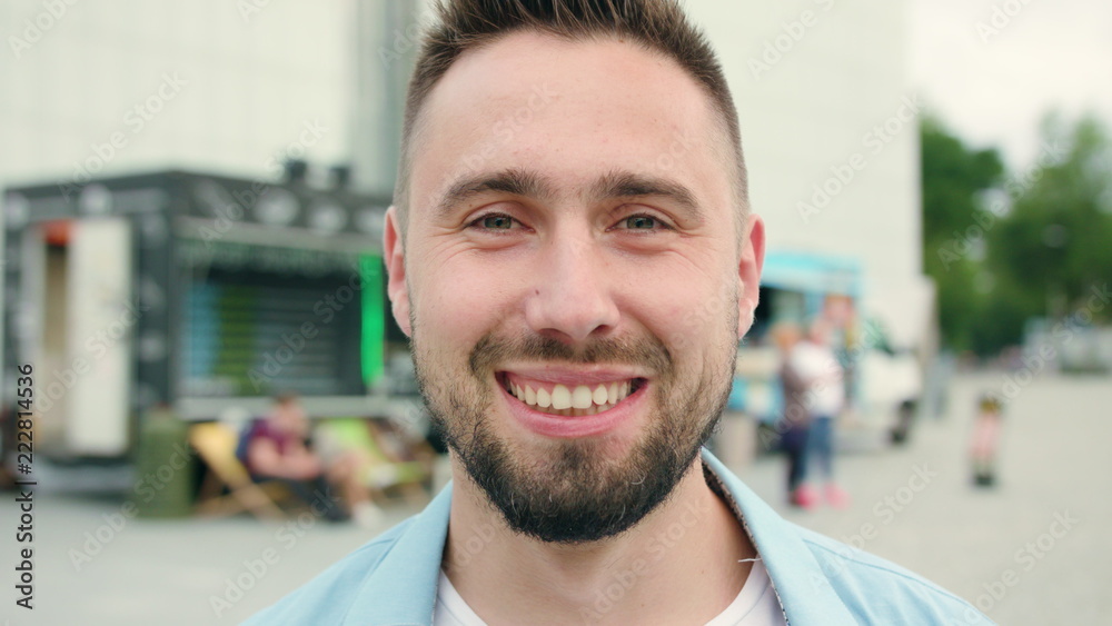 A man with a beard smiling in the city street full of people. Close-up shot. Soft focus A man with a beard smiling in the city street full of people. Close-up shot. Soft focus