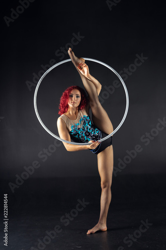 Young attractive girl keep split holding a hoop.
