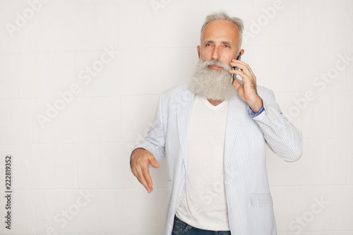 Studio shot of happy senior bearded businessman smiling while using mobile phone with against white background