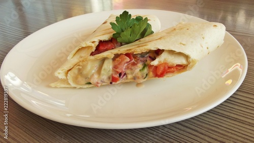 Fresh vegetables in pita bread on a white plate.