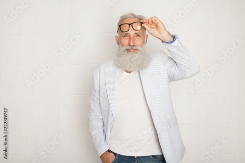 Cheerful happy mature man in glasses looking camera and smiling over white wall photo