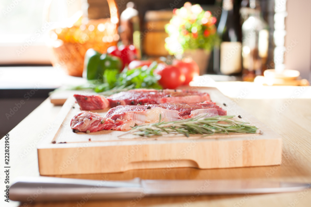 Raw beef tenderloin steak on a cutting board with rosemary pepper salt fork and cutter. Raw beef tenderloin steak on a cutting board with rosemary pepper salt fork and cutter.