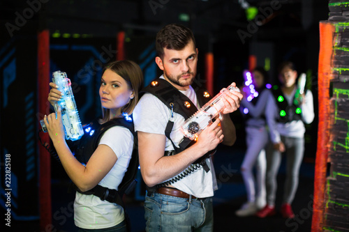 Man and woman standing back to back with laser pistols
