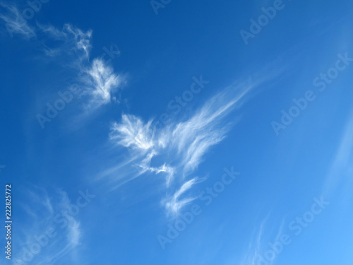 Blue sky with white cirrus clouds. Beautiful weather background