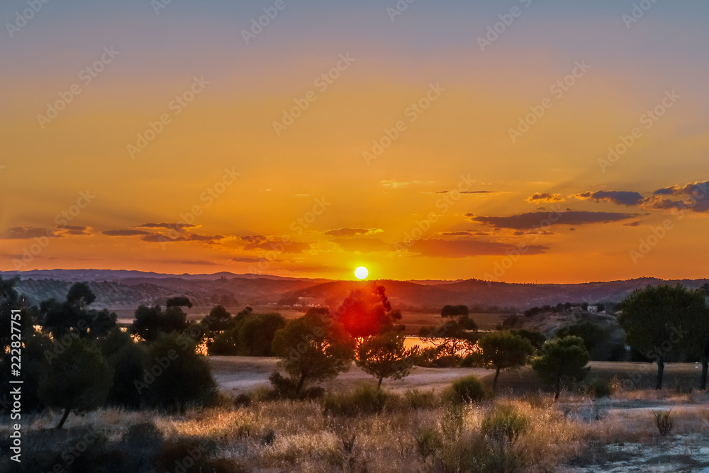 Fototapeta Golden sunset with rays in the haze and clouds in Ayamonte, Andalucia, Spain looking accross to Portugal over the Guadiana River seen from Costa Esuri