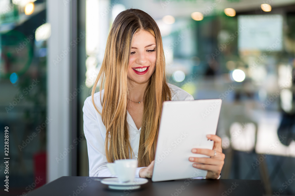 Young businesswoman on a coffee break. Using tablet computer.