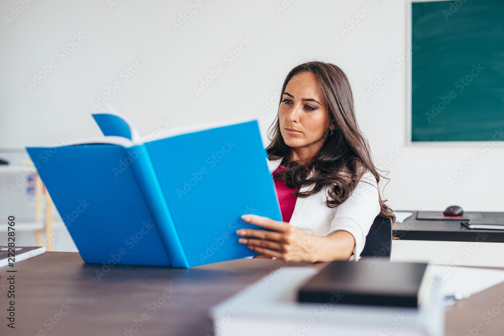 Young woman sitting by table and reading book. Young woman sitting by table and reading book.