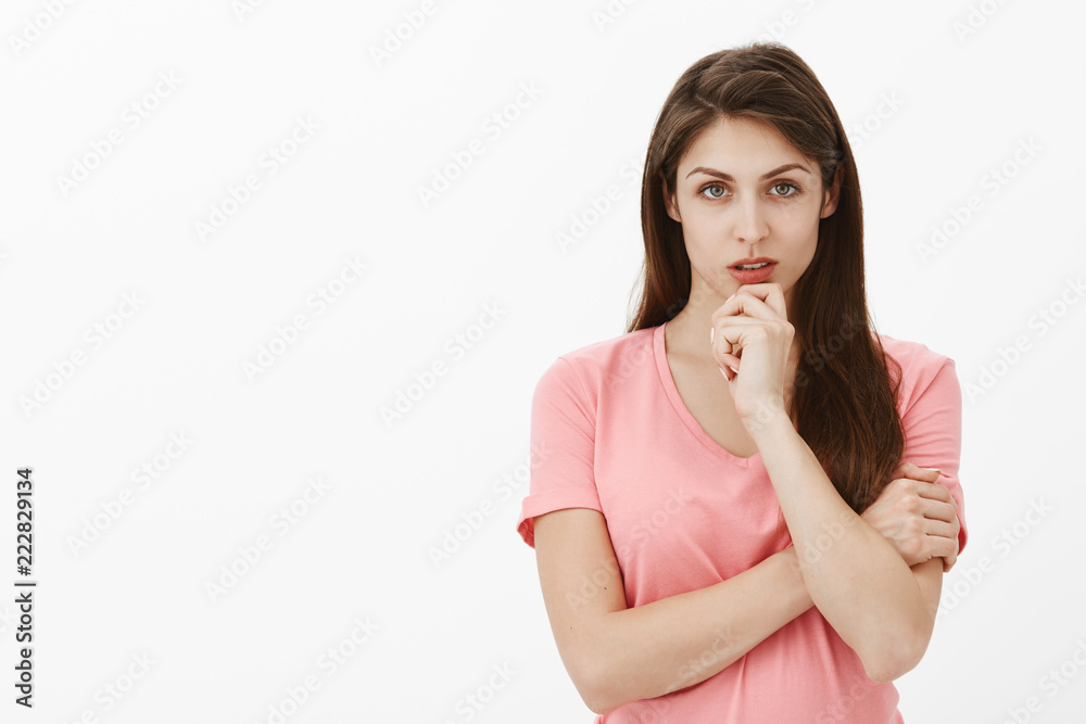 Girl stuck in tough situation, thinking how to solve problem. Portrait of focused intense smart and beautiful woman in pink t-shirt, holding arm crossed and touching chin while gazing strict at camera Girl stuck in tough situation, thinking how to solve problem. Portrait of focused intense smart and beautiful woman in pink t-shirt, holding arm crossed and touching chin while gazing strict at camera