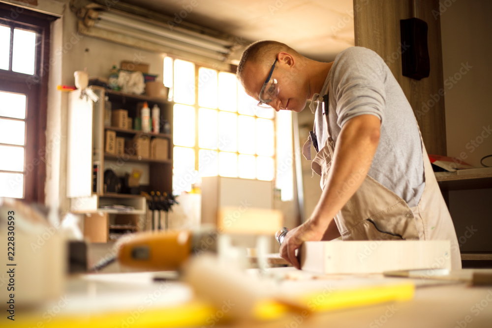 Carpenter working on woodworking machines in carpentry shop Carpenter working on woodworking machines in carpentry shop