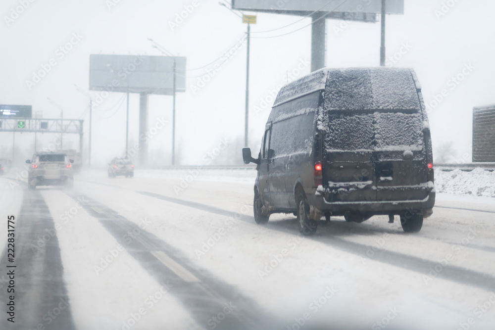 Car with lights on a snow covered road.