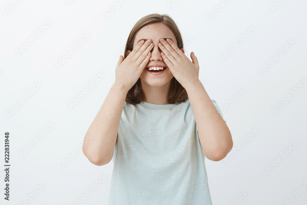 Girl counting to ten ready to seek friends while playing hide-and-seek. Portrait of joyful and emotive cute woman in light-blue t-shirt waiting for surprise with closed eyes and palms on sight smiling Girl counting to ten ready to seek friends while playing hide-and-seek. Portrait of joyful and emotive cute woman in light-blue t-shirt waiting for surprise with closed eyes and palms on sight smiling