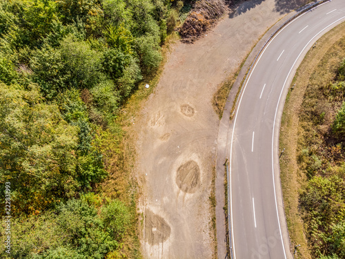Aerial view of a lonely asphalted country road in the Harz Mountains with a neighbouring forest and the basin of a dam