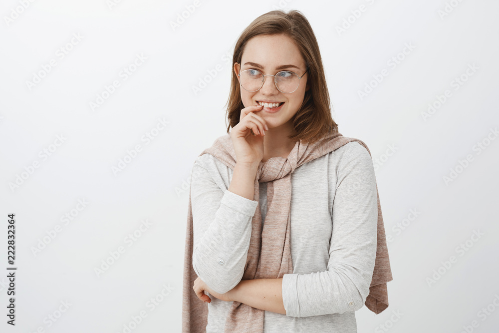 Girl looking at curious guy trying turn attention biting finger and smiling intrigued gazing left with interest and desire having mysterious delightful idea standing over gray background Girl looking at curious guy trying turn attention biting finger and smiling intrigued gazing left with interest and desire having mysterious delightful idea standing over gray background