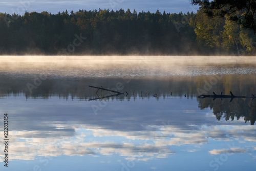 Sunshine over a lake in the background of the forest. Autumn sunrise in Lithuania.