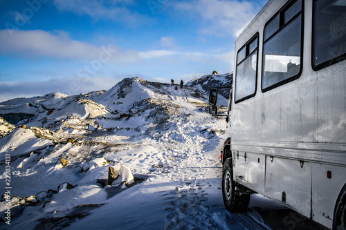 KANGERLUSSUAQ, GREENLAND - Oct 2009: An overland truck waits for tourists as they trek along a snowy ridge towards the inland ice cap near Kangerlussuaq in west Greenland